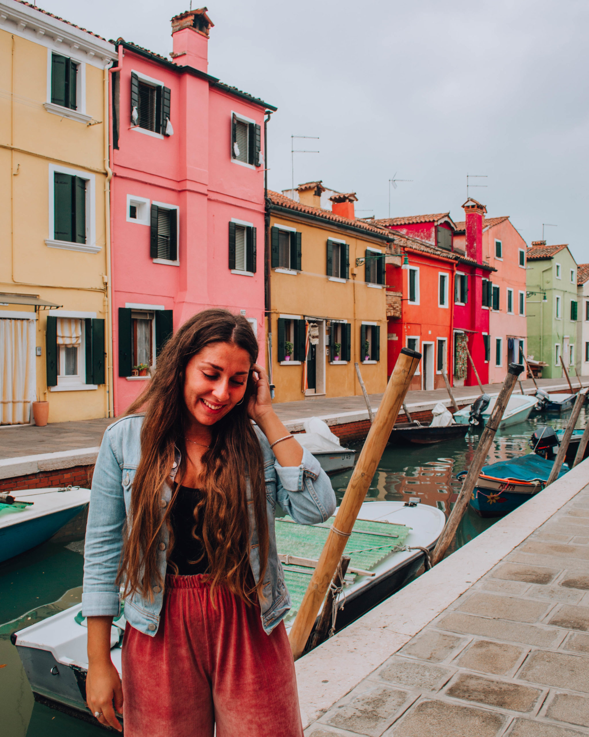 ragazza con giacca di jeans davanti ad un canale d'acqua e case colorate