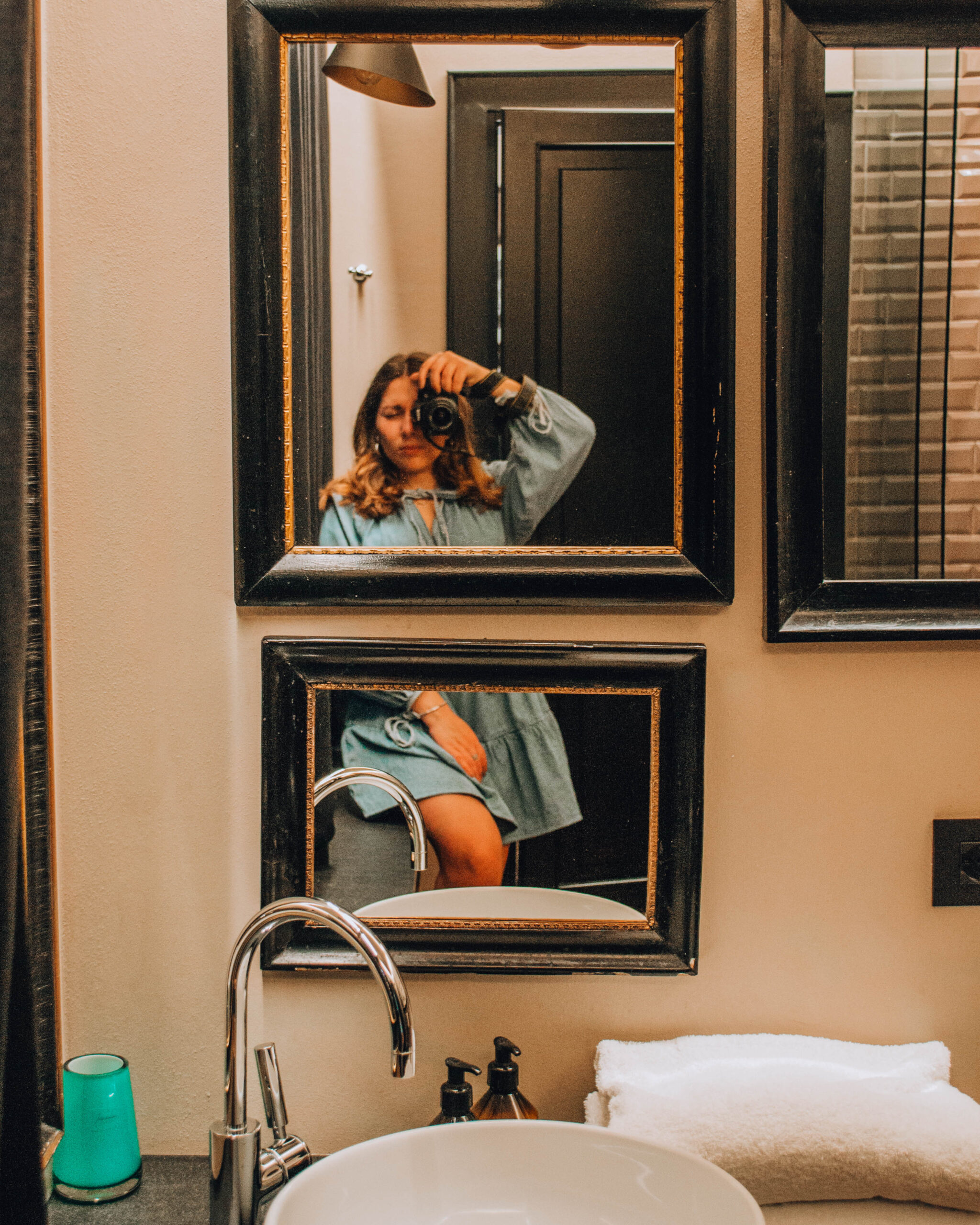 ragazza con abito azzurro che si fotografa allo specchio di un bagno
