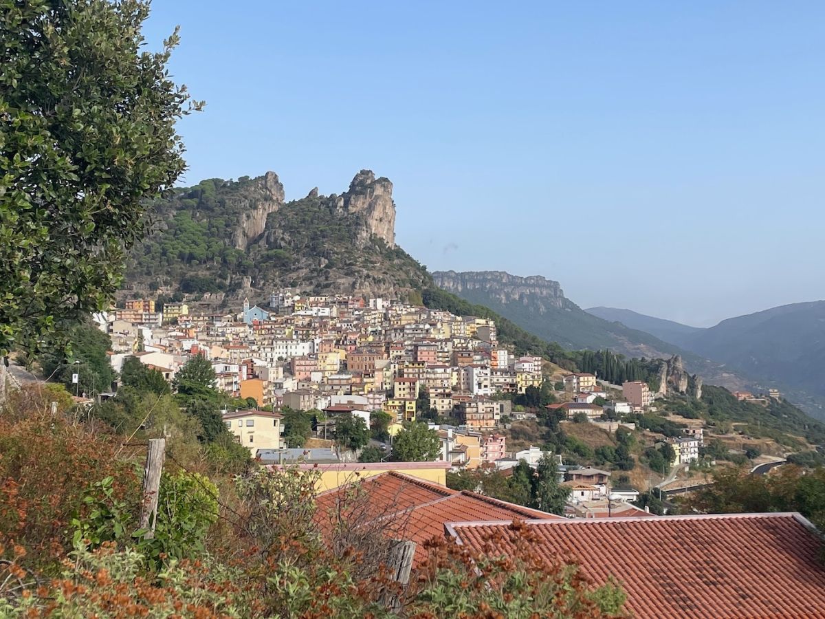 Veduta panoramica del borgo di Ulassai, cosa vedere assolutamente in Ogliastra, con le sue caratteristiche case bianche e tetti in terracotta, sovrastato dai maestosi tacchi calcarei sotto un cielo azzurro limpido.
