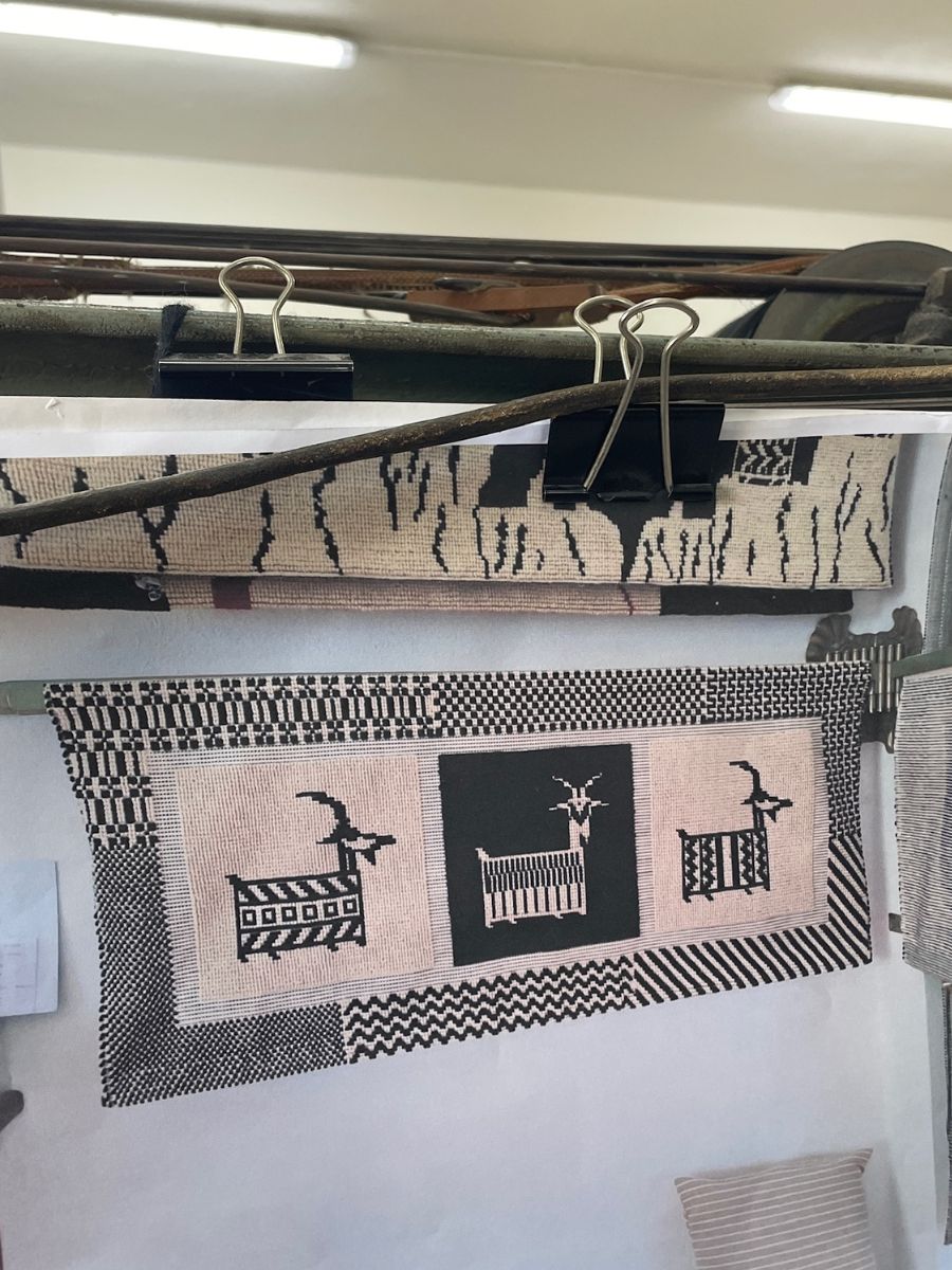 Un tappeto sardo tradizionale in bianco e nero appeso a un telaio nel laboratorio di tessitura Su Marmuri, una delle principali attrazioni da vedere a Ulassai. Presenta motivi stilizzati di capre e disegni geometrici.